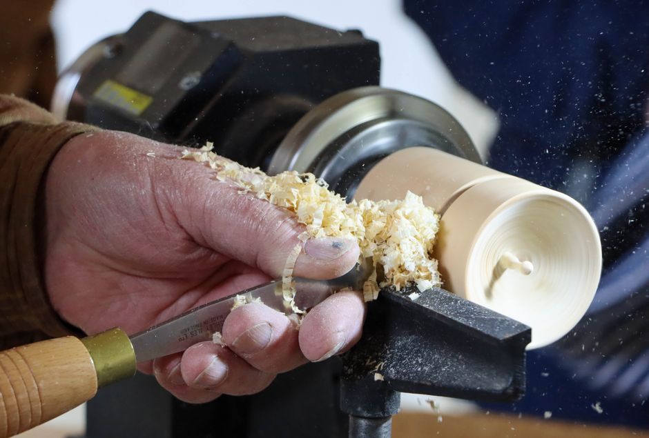 Hände beim Schnitzen eines Kochlöffels aus frischem Holz